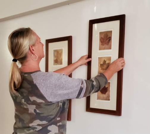Hanging a picture in a newly furnished apartment that was furnished by the New Directions Program.