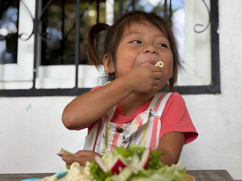 Sponsorship child eating her food at the weekly feed program at the HIM nutrition center in Gualan, Guatemala.