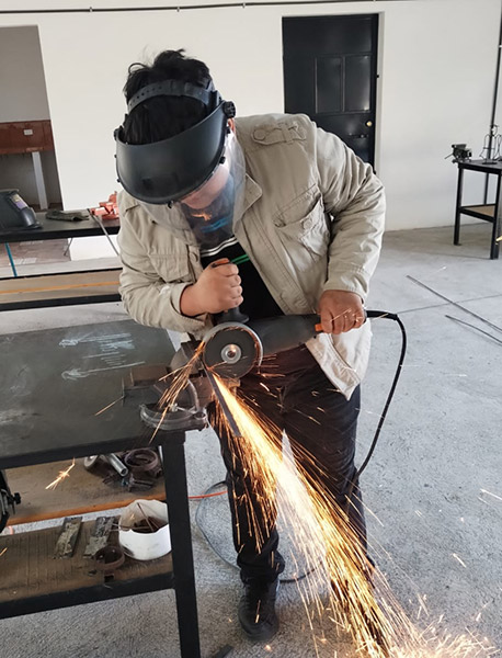 Teacher using grinder at trade school on Gualan Campus